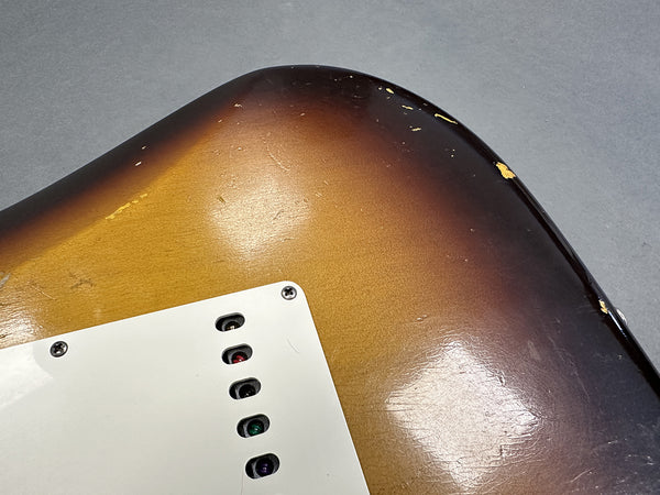 Close-up of vintage sunburst electric guitar body with white backplate showing wear and paint chips