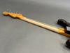 Vintage electric guitar neck with six tuning pegs, maple wood fretless neck with skunk stripe, and part of a worn dark finished guitar body on gray background.