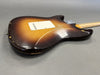 Vintage sunburst electric guitar body with aged wear and scratches, showing back panel and neck heel on gray background