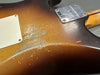 Close-up of worn sunburst finish on the back of a Fender Custom Shop electric guitar body with neck plate and screws visible.