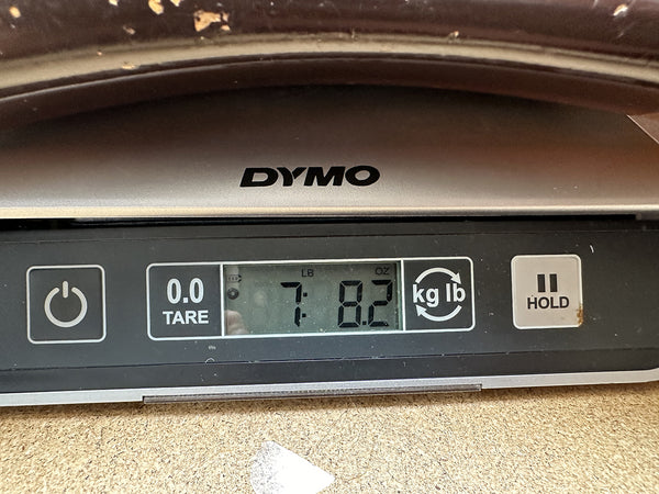 Close-up of DYMO digital scale display showing guitar weight as 7 pounds 8.2 ounces for Coffee House Guitars product listing.