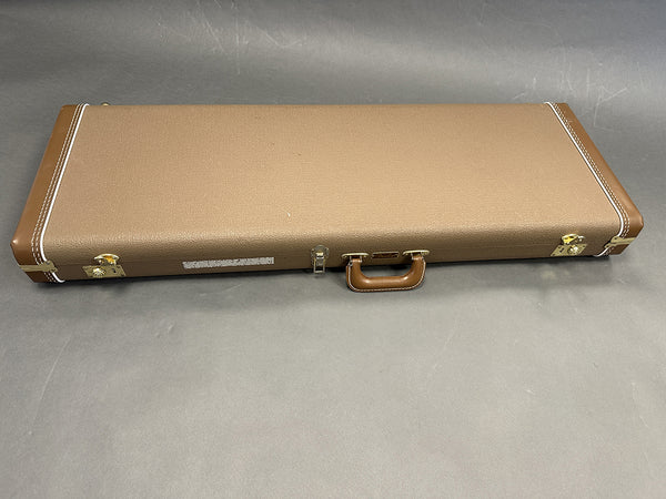 Brown Fender guitar hard case with white stitching and gold hardware on grey background