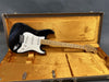 Black Fender Stratocaster electric guitar with maple neck and white pickguard inside vintage orange plush-lined brown hardshell case