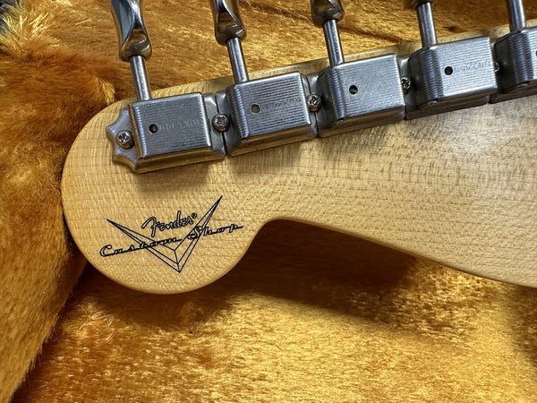 Close-up of Fender Custom Shop guitar headstock with vintage-style tuning machines on plush orange case lining