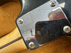 Close-up of guitar neck plate with serial number R74690 on maple neck with walnut stripe and black guitar body background
