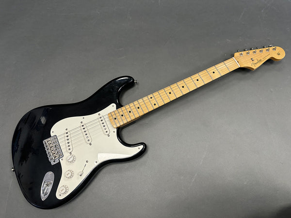 Black Fender Stratocaster electric guitar with maple neck and white pickguard on gray background