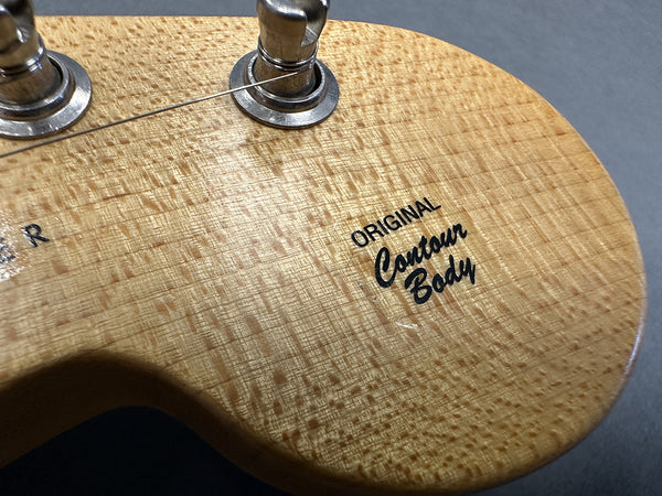 Close-up of guitar body with Original Contour Body decal and tuning pegs, showing detailed wood grain texture