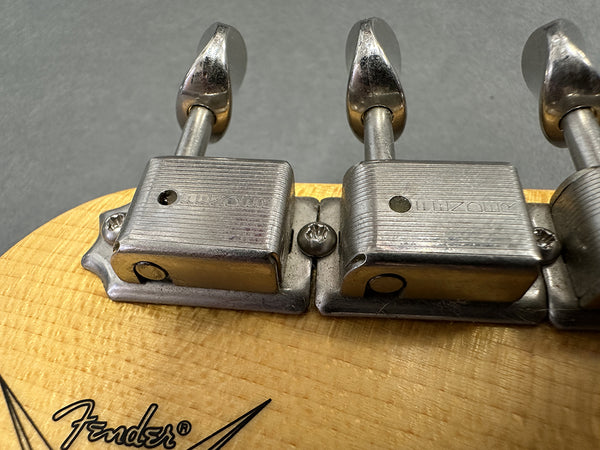 Close-up of vintage Kluson tuning pegs on a Fender guitar headstock with natural wood finish and Fender logo visible