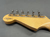 Close-up of vintage Fender Custom Shop guitar headstock with six tuning pegs and natural wood finish on gray background