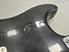 Close-up of black electric guitar body corner showing detailed wear, cracks, and finish checking on the surface