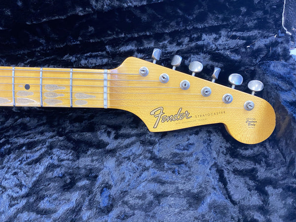 Close-up of vintage Fender Stratocaster maple guitar neck and headstock with six tuning pegs on black plush background