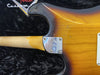 Close-up of Fender Custom electric guitar neck joint showing sunburst finish, chrome neck plate with Fender logo, and aged wear marks on guitar body and maple neck against black plush case interior.