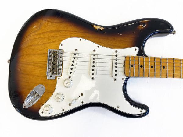 Vintage sunburst electric guitar with white pickguard, three single-coil pickups, volume and tone knobs, and maple neck, showing signs of wear and aging