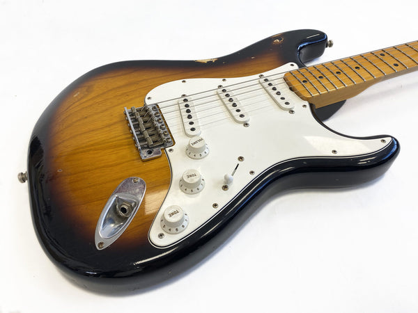 Vintage sunburst electric guitar with white pickguard, three single-coil pickups, volume and tone control knobs, maple neck and fretboard, shown on white background