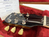 Close-up of Gibson Les Paul guitar headstock with vintage-style tuning pegs and serial number card inside red plush-lined guitar case