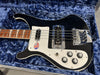 Black electric bass guitar with white pickguard, chrome bridge, and control knobs in a blue plush-lined guitar case