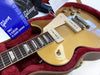 Close-up of Gibson electric guitar with gold top finish and P90 pickups in red plush-lined hard case with Gibson polishing cloth and accessories