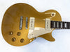 Gold electric guitar with cream-colored pickups and pickguard, four control knobs, and rosewood fretboard with rectangular inlays on white background