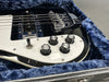 Close-up of black electric bass guitar control knobs and pickup inside blue plush lined guitar case