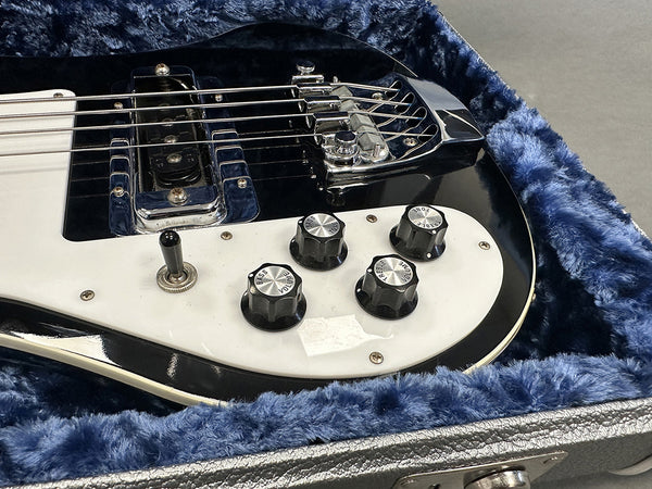 Close-up of black electric bass guitar control knobs and pickup inside blue plush lined guitar case