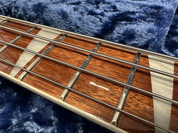 Close-up of acoustic bass guitar fretboard with metal frets and strings on a blue plush surface