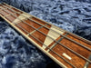 Close-up of bass guitar fretboard with metal frets and four strings on soft blue fabric background
