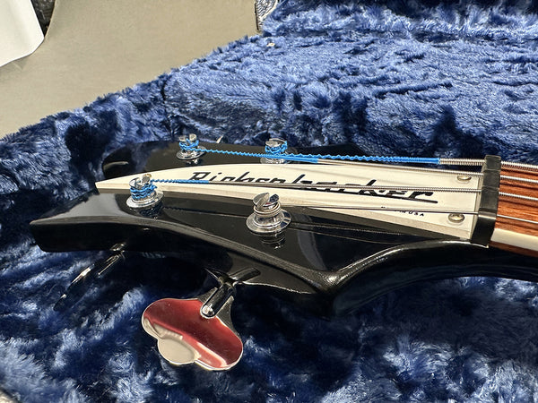 Close-up of black Gibson Bass guitar headstock with tuning pegs and blue-wrapped bass strings resting on blue plush guitar case lining