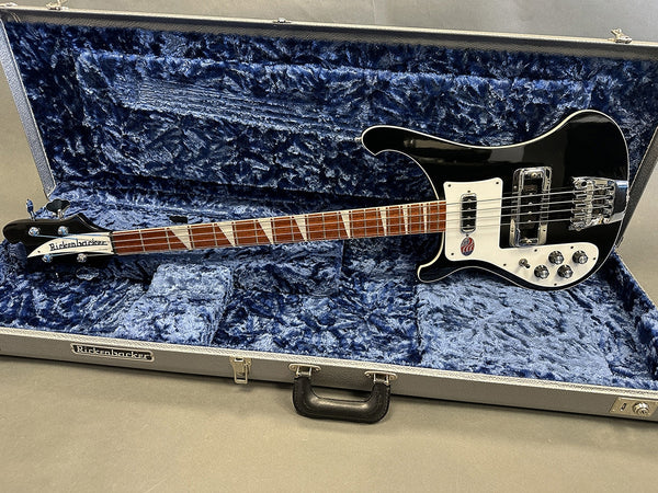 Rickenbacker black electric bass guitar with white pickguard and triangular inlays in plush blue lined hard case on grey background