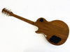 Back view of brown electric guitar with wooden finish and black control cavity covers on white background