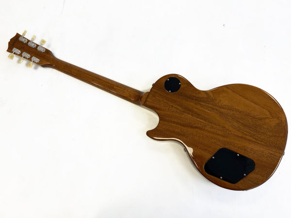 Back view of brown electric guitar with wooden finish and black control cavity covers on white background