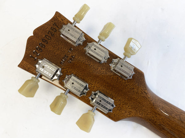 Back of guitar headstock showing Grover tuning machines with vintage-style tulip buttons, serial number 129890267 stamped in mahogany wood, "Made in USA" imprint on natural wood grain finish