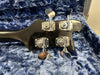Close-up of black bass guitar headstock with four chrome tuning pegs in blue plush guitar case lining