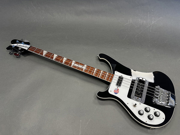 Black Rickenbacker electric bass guitar with white pickguard and triangular fret inlays on wooden neck