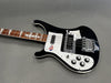 Black and white electric bass guitar with rosewood fretboard and four control knobs on gray background