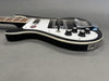 Black electric bass guitar with white pickguard and chrome hardware on gray background