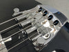 Close-up of chrome bridge and strings on black electric bass guitar showing detailed string saddles and adjustment knobs