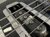 Close-up of electric guitar bridge and pickup with metal strings and chrome hardware on black guitar body