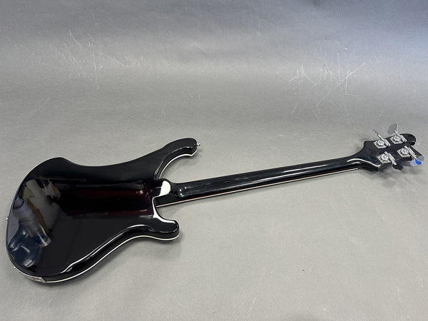 Back view of black electric bass guitar with glossy finish and chrome tuning pegs on gray background