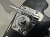 Close-up of Rickenbacker bass guitar chrome tuning machine gear and tuning key on black headstock with visible screws and engraved brand name