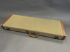 Vintage tweed guitar hard case with brown leather handle and corner reinforcements on gray background