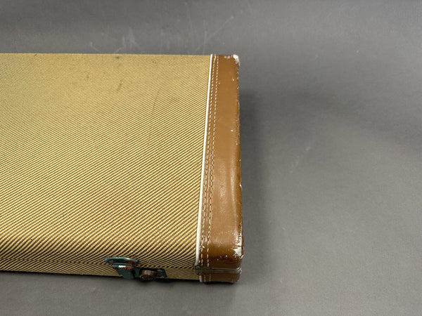 Vintage tweed guitar case with brown leather edges and metal latch on gray background