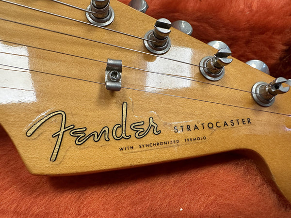 Close-up of Fender Stratocaster guitar headstock with tuning pegs and synchronized tremolo logo on natural wood finish