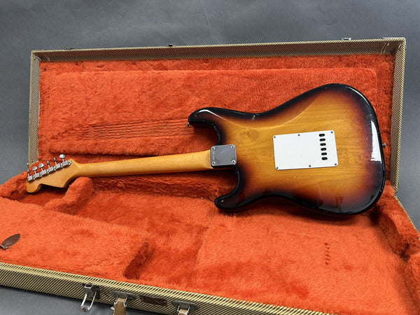 Vintage sunburst electric guitar with maple neck and tuning pegs inside orange plush-lined tweed guitar case viewed from back