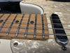 Close-up of electric guitar maple fretboard with black dot inlays, steel frets, and strings, featuring cream-colored pearloid pickguard and single-coil pickup.