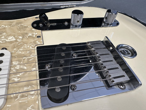 Close-up of white electric guitar bridge and pickups with chrome hardware and pearloid pickguard from Coffee House Guitars