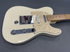 Cream colored electric guitar with maple fretboard and pearl pickguard, vintage-style bridge and chrome control knobs on dark background