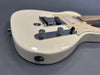 Close-up of cream-colored electric guitar body showing chrome knobs, pickup, and input jack on gray background