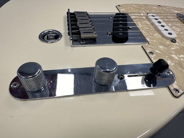 Close-up of white electric guitar control plate with two knurled chrome knobs and black pickup selector switch near bridge and pickups