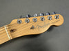 Close-up of Fender Telecaster guitar headstock with tuning pegs and maple wood finish on gray background
