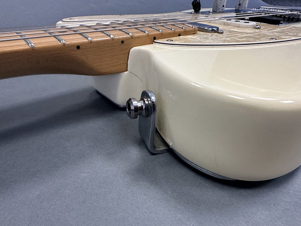 Close-up of cream electric guitar body and maple neck with chrome strap button on gray background